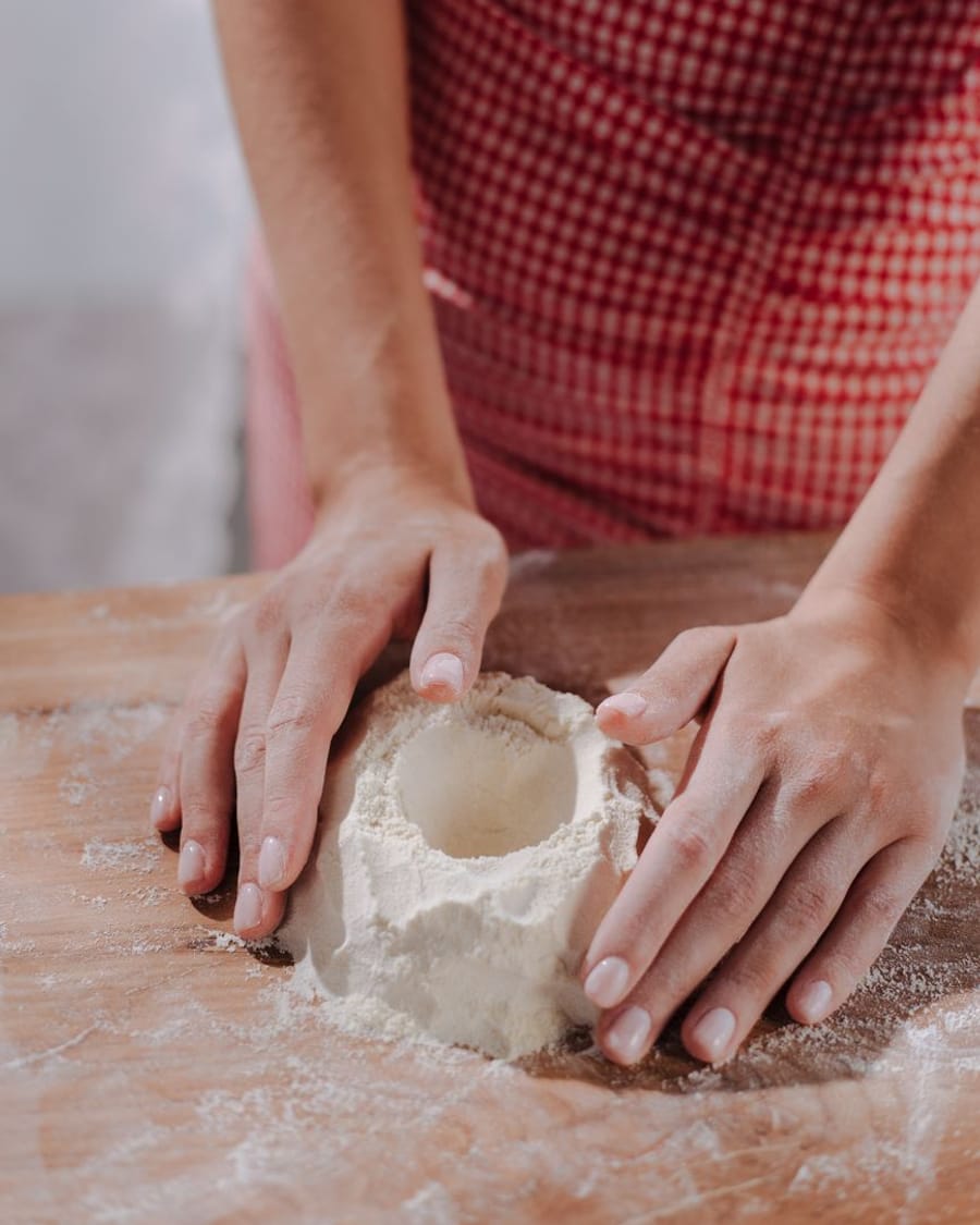 Mani che impastano la pasta fresca sul tagliere