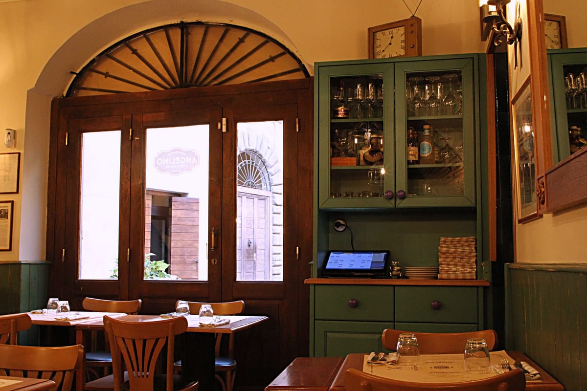 Sala dell'osteria con arco, legno e luci calde